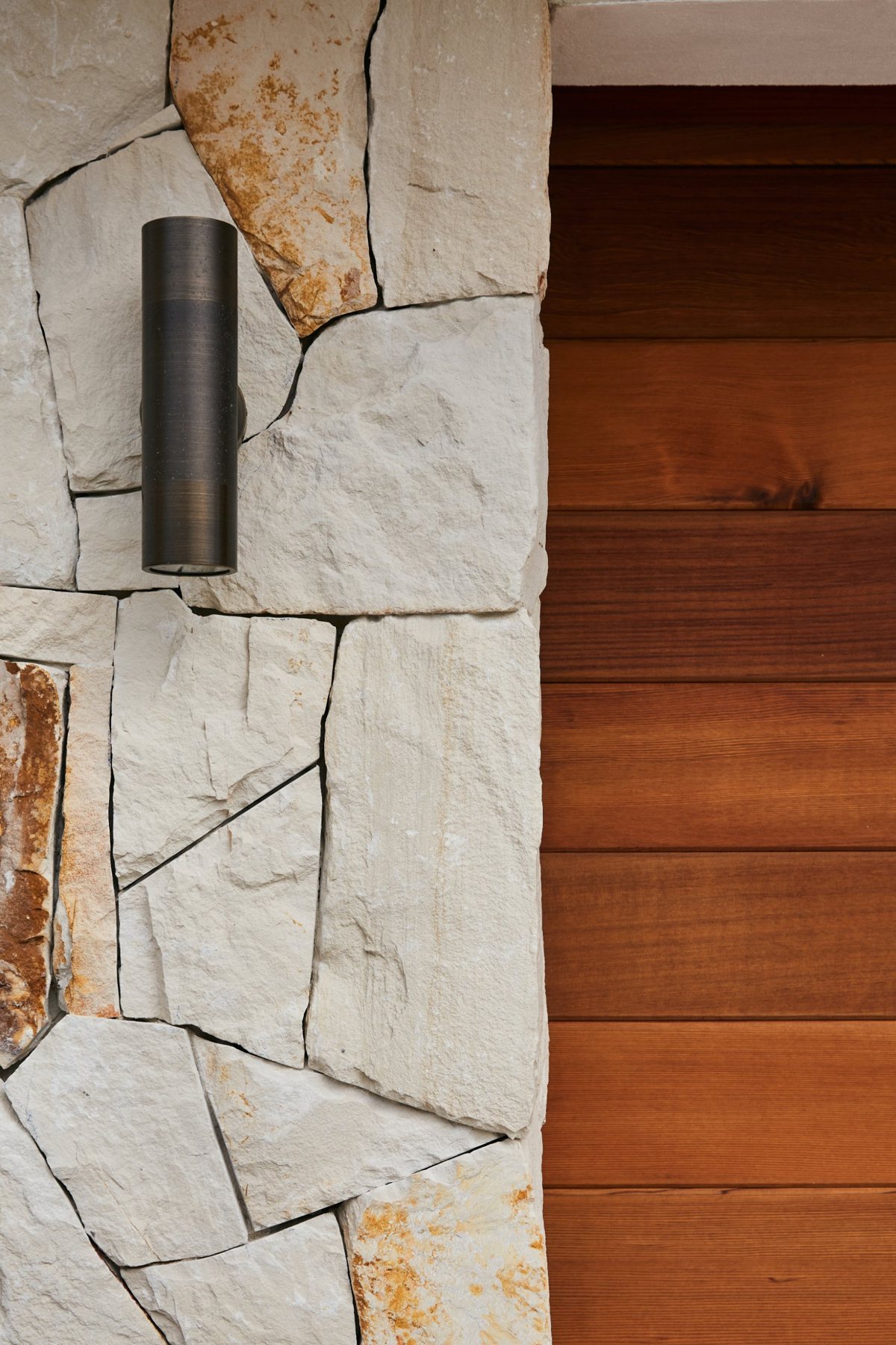 Bronze up and down wall light on a sandstone pier beside cedar cladding