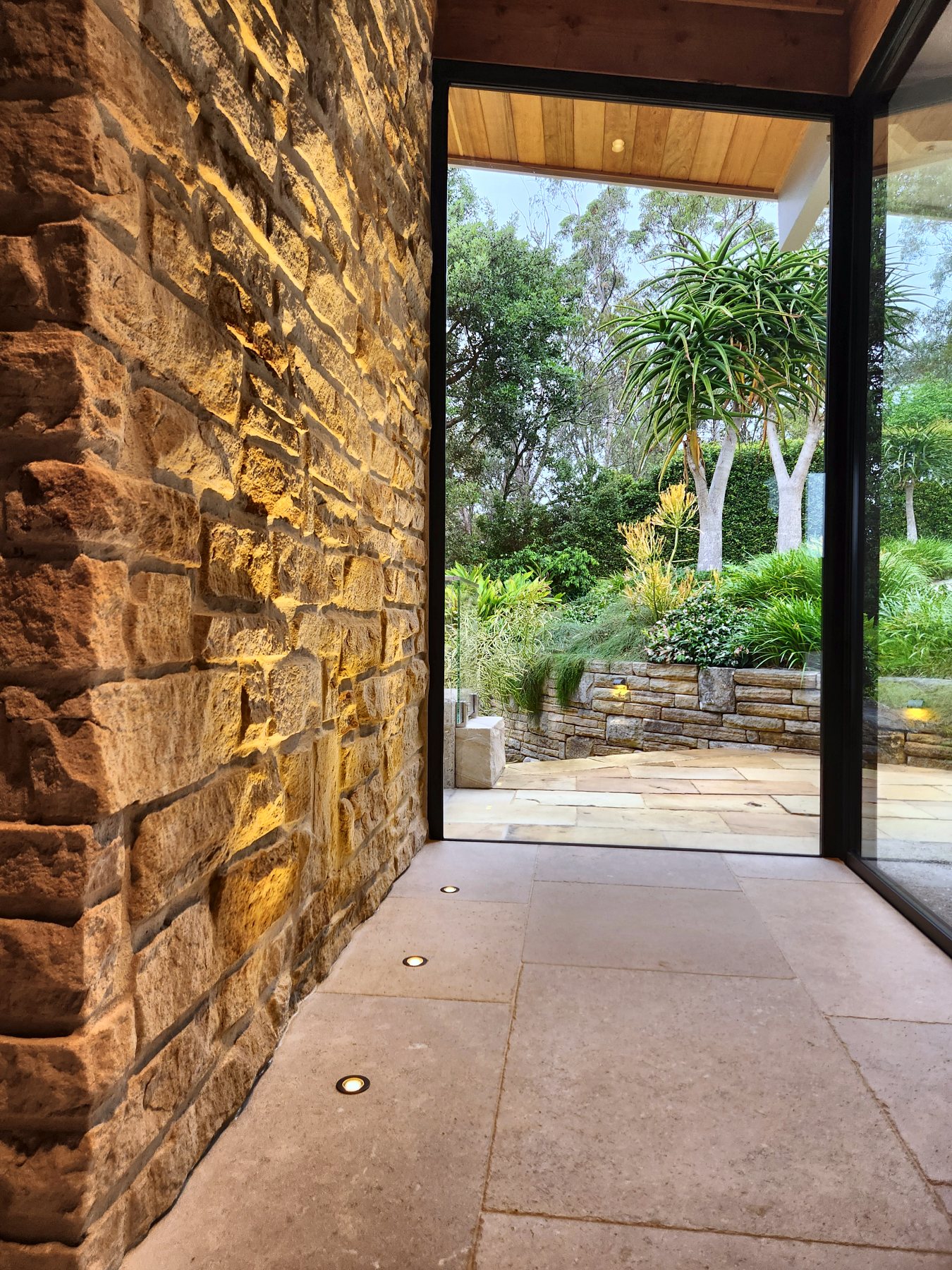 Lit sandstone wall leading out to the garden